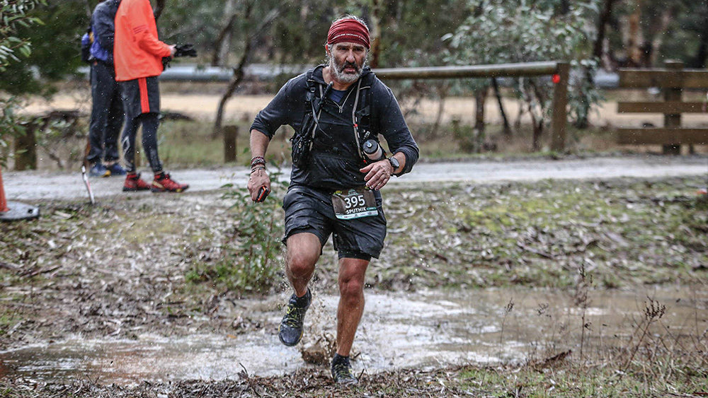 Man running a race in cold and wet conditions