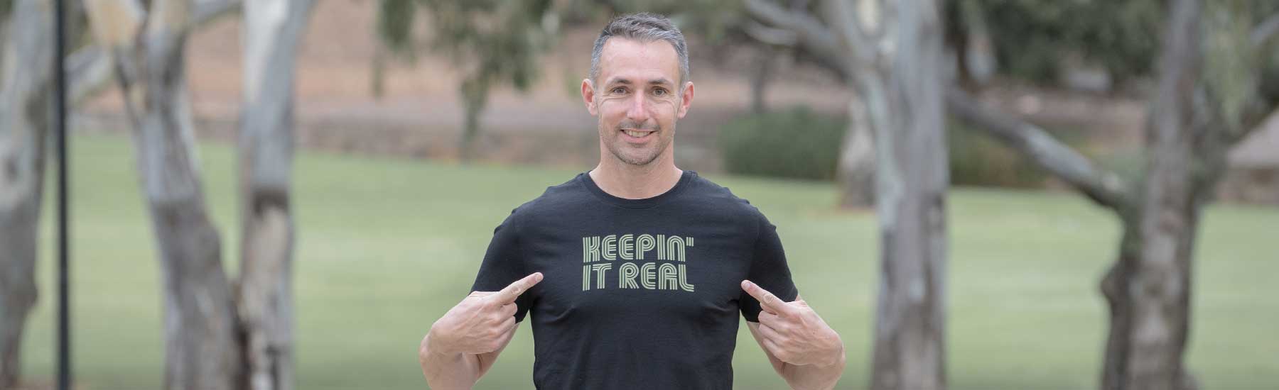 Man pointing to a Keepin' It Real design print on his tshirt