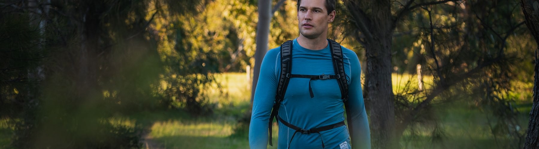 Man hiking outdoors in a blue long sleeve top and wearing a backpack