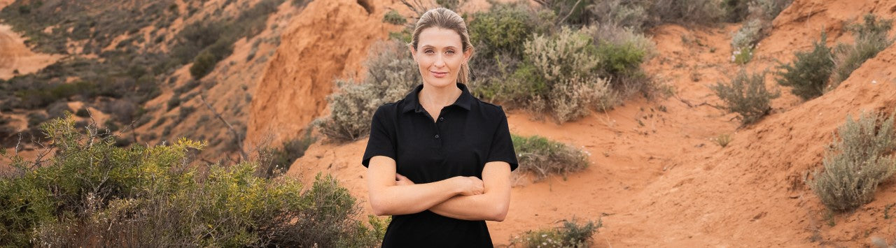 Woman wearing black merino wool polo shirt standing in country Australia
